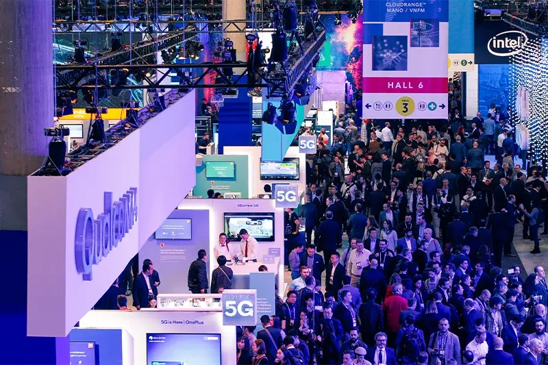 Crowded exhibition hall at MWC Barcelona with 5G and technology vendor stands including Qualcomm and Intel